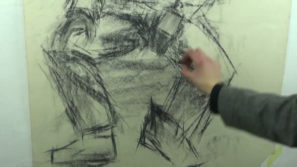 Drawing a fast sketch of a man with a cap with a black charcoal stick — 图库视频影像