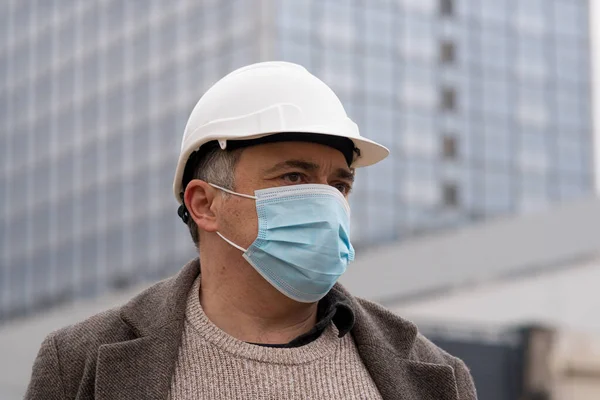 Engineering during COVID-19 (Coronavirus SARS-CoV-2) outbreak. Occupational safety and health and protection against adverse conditions at work. Construction worker wearing hardhat and medical mask