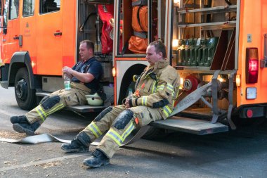 Berlin, Almanya - 6 Ağustos 2020: Berliner itfaiyecileri bir operasyondan sonra bitkin halde oturuyorlar