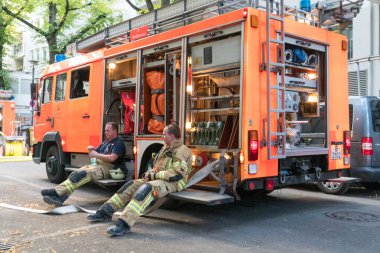 Berlin, Almanya - 6 Ağustos 2020: Berliner itfaiyecileri bir operasyondan sonra bitkin halde oturuyorlar