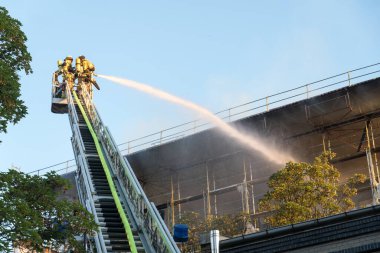 Berlin, Almanya - 6 Ağustos 2020: İtfaiyeciler yangına karşı merdiven tırmanıp yangını söndürüyorlar