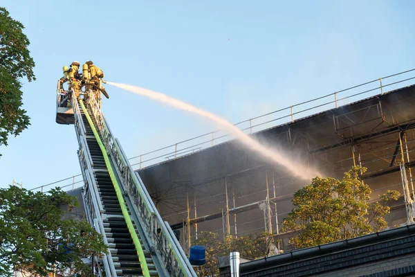Berlin, Almanya - 6 Ağustos 2020: İtfaiyeciler yangına karşı merdiven tırmanıp yangını söndürüyorlar