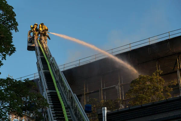 Berlin, Almanya - 6 Ağustos 2020: İtfaiyeciler yangına karşı merdiven tırmanıp yangını söndürüyorlar