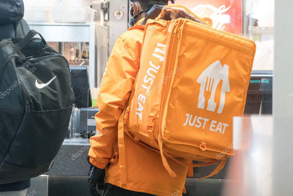 Rome, Italy - January 27, 2021: Just Eat delivery man at work on bike. Just Eat is an online food order and delivery service intermediary between independent take-out food outlets and customers