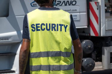 Formia, İtalya - 15 Temmuz 2021: Tanımlanamayan sırt, sarı yansıtıcı önlük giyen bir güvenlik görevlisine dönüştü