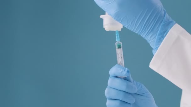Sobre un fondo azul, una enfermera introduce una solución medicinal en una jeringa para la vacunación y el tratamiento de pacientes.. — Vídeos de Stock
