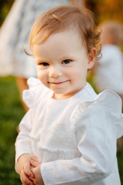 Beyaz pamuklu elbise giymiş 2 yaşında sarışın bir kızın portresi..