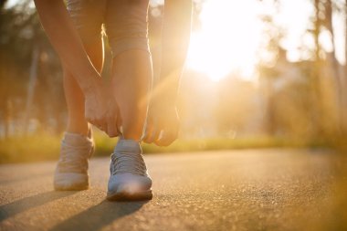 Antrenmandaki sporcu koşu ayakkabılarındaki bağcıkları bağlar..