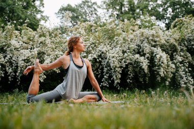Kadın bacaklarını ve sırtını esnetmekle meşgul..