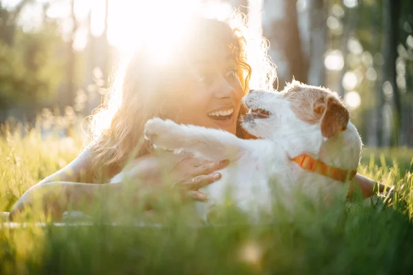 Köpekli bir kadın parkta çimlerin üzerinde dinleniyor..