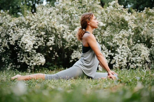 De yoga ruiter pose wordt uitgevoerd door een meisje in het park. Rechtenvrije Stockafbeeldingen