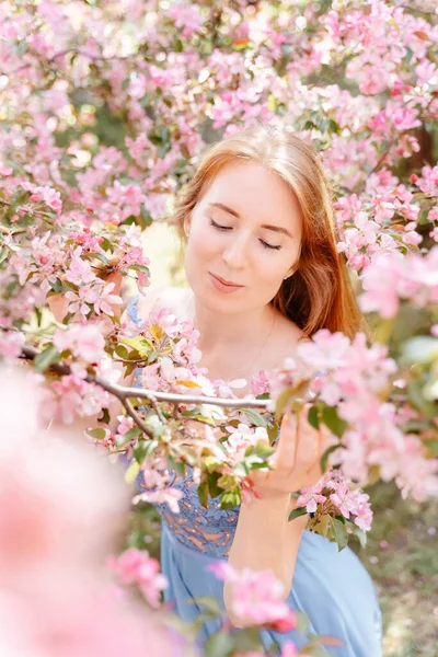 女孩在花园里吸入樱花的芬芳而不会对花粉过敏 — 图库照片