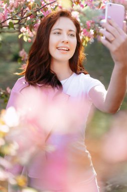 Gülümseyen kız parkta telefonla konuşuyor..