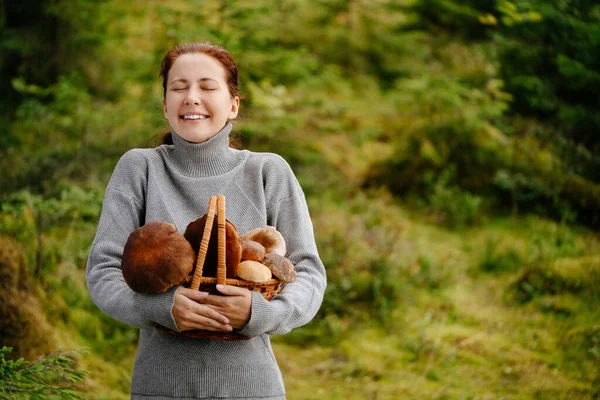 숲 속에 여러 버섯이 담긴 바구니를 들고 있는 여자 스톡 사진