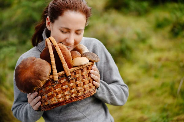 Vrouw met een mand paddenstoelen in het bos Stockfoto