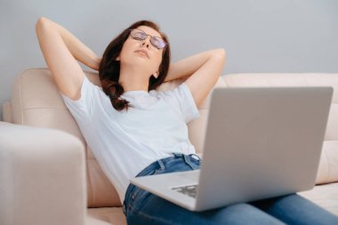 Genç serbest çalışan kadın evdeki kanepede dinleniyor..