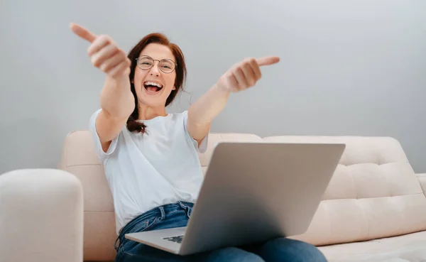 Donna sorridente dà un pollice verso l'alto per la fotocamera mentre seduto con un computer. — Foto Stock