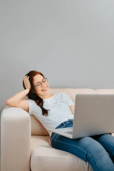 Een vrouw kijkt online films via een laptop thuis. Stockfoto