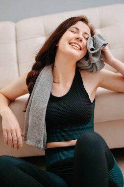 Genç sporcu evde spor yaptıktan sonra terini havluyla siler..