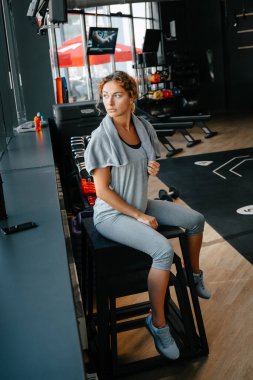 Kadın sporcu vücut çalışmasından sonra havluyla dinleniyor..