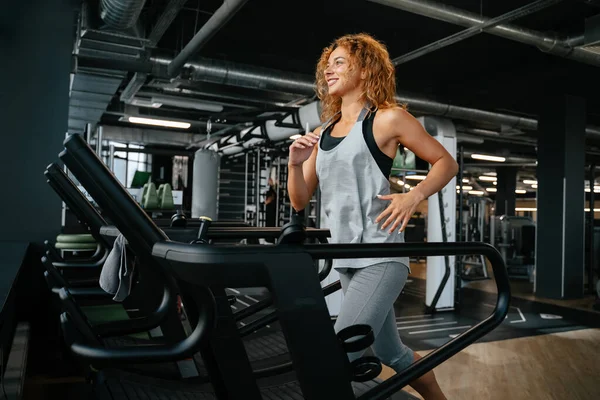 Žena běhání na běžeckém pásu v tělocvičně se zabývá fitness. — Stock fotografie