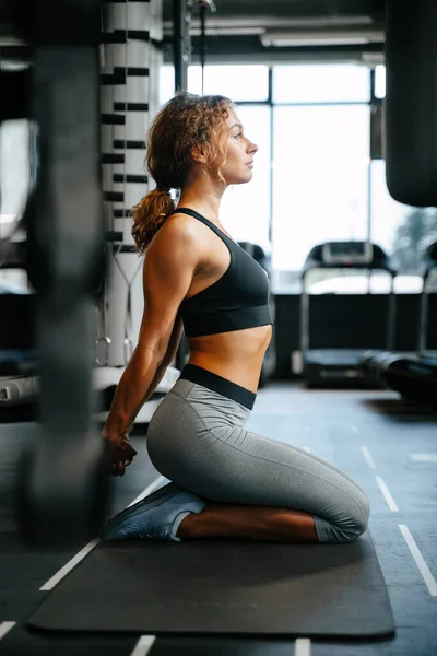 Mladá žena ve sportovním oblečení dělá jógu v tělocvičně sedí na podlaze. — Stock fotografie