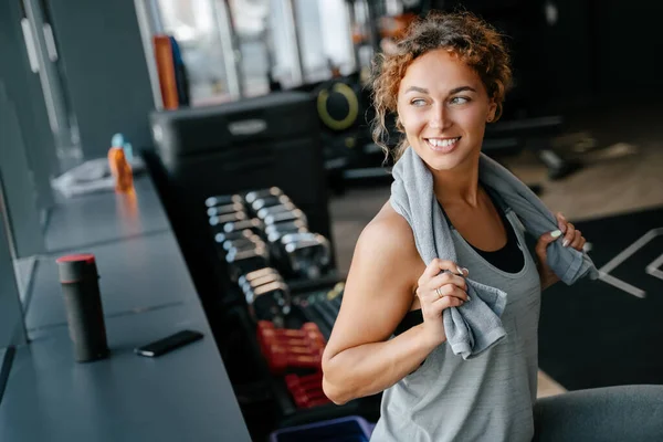 Femme heureuse après une séance d'entraînement intense dans la salle de gym se repose avec une serviette. Photo De Stock