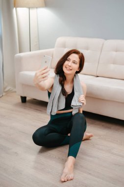 Yogadan sonra havluyla egzersiz yapan kadın telefonda kendi fotoğrafını çekiyor..