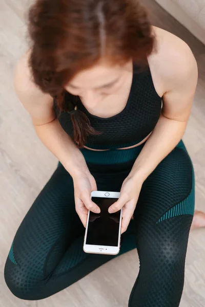 Sportovec sedí doma po tréninku rozhovory po telefonu s přáteli. — Stock fotografie