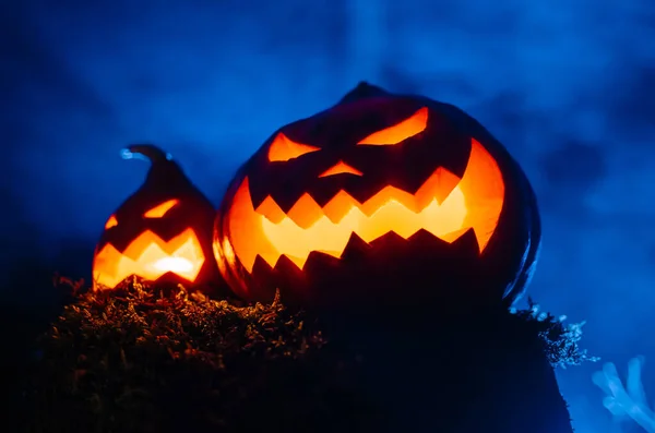 Zwei leuchtende Laternen sind orange-blaue Gruselkürbisse mit Rauchwald. — Stockfoto