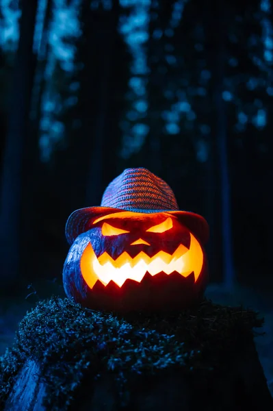 Ein gruseliger Kürbis mit geschnitztem Gesicht in einem düsteren Wald an Halloween. — Stockfoto