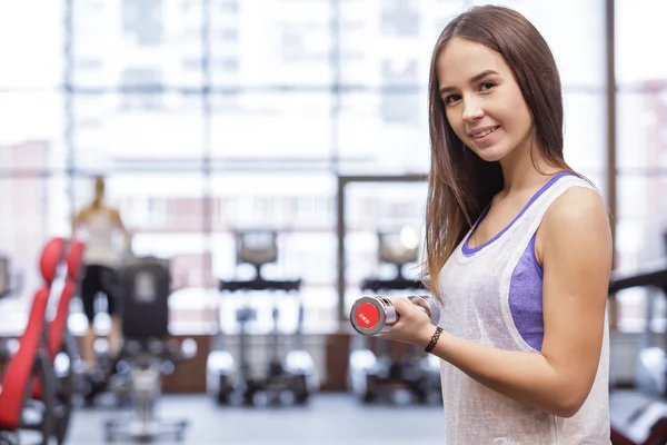 Mujer joven haciendo ejercicio con pesas en un gimnasio —  Fotos de Stock