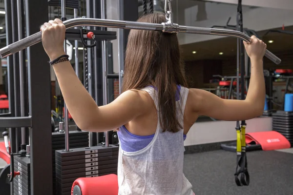 Mujer joven haciendo ejercicios sobre el aparato de entrenamiento —  Fotos de Stock