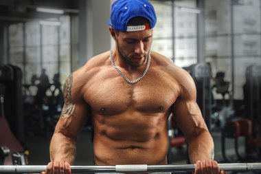 Barbell ile egzersiz yaparak genç kaslı adam.