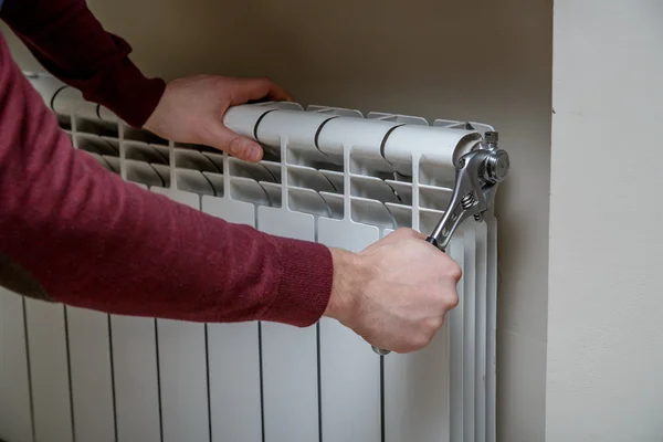 Trabalhador mãos reparando radiador com chave . — Fotografia de Stock
