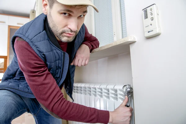 Male plumber repairing radiator with wrench. — Stock Photo, Image