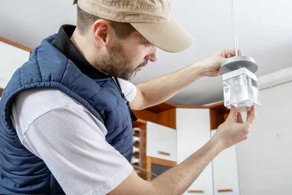 A male electrician fixing light on the ceiling. — Stock Photo, Image