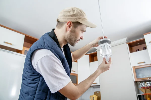 A male electrician fixing light on the ceiling. — Stock Photo, Image