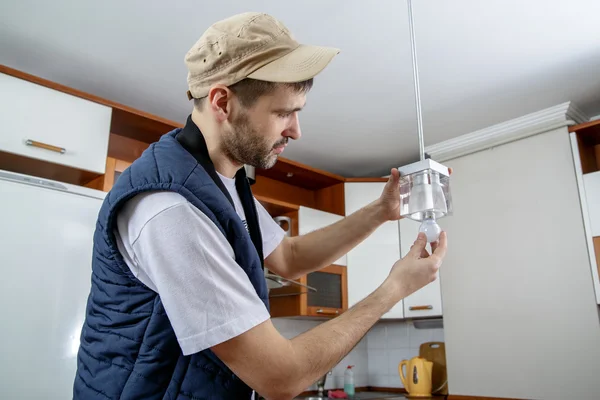 A male electrician fixing light on the ceiling. — Stock Photo, Image
