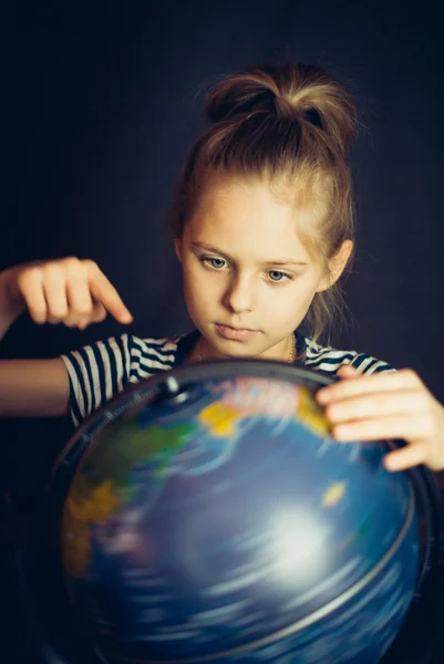 Beautiful little girl twirls globe — Stock Photo, Image