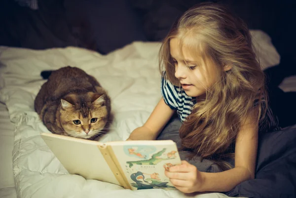 Gülümseyen kız kitap bir kedi için okur.