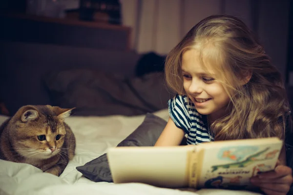 Gülümseyen kız kitap bir kedi için okur.
