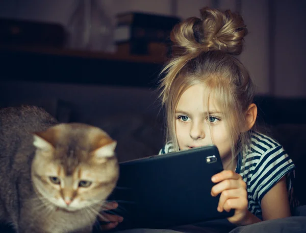 Holding a tabletta a gyönyörű lány, és úgy néz ki, a macska — Stock Fotó
