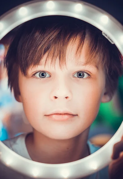 Surprised boy looking at the camera through a luminous circle as an astronaut — Stock Photo, Image