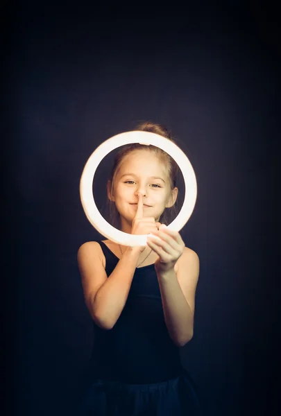 Beautiful young girl gymnast holding a glowing circle and making quiet gesture — Stock Photo, Image