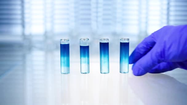 Laboratório. Mão na luva azul move os tubos e goteja líquido azul — Vídeo de Stock