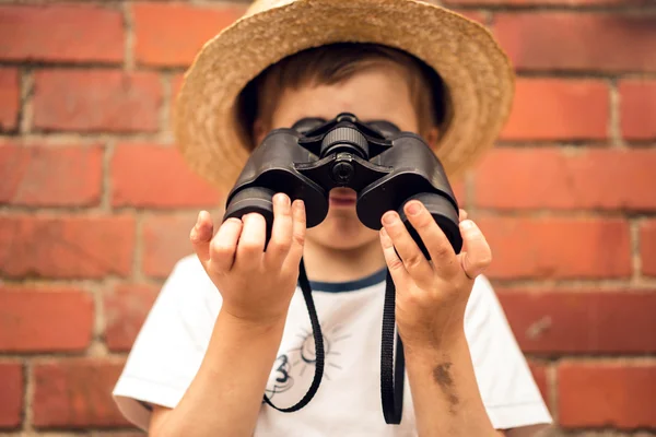 Boy in a straw hat looks in binoculars — Stock Photo, Image