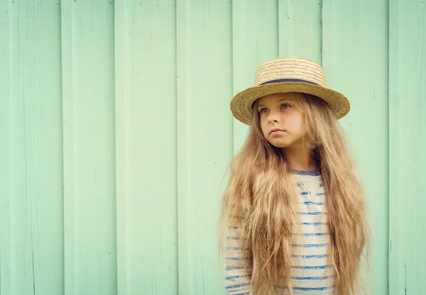 Aranyos kislány kalap zsirardikalap türkiz fal közelében áll, és pensively néz félre. Hely a szöveg — Stock Fotó