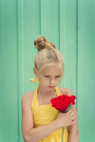 Triste joven rubia sosteniendo una flor roja — Foto de Stock