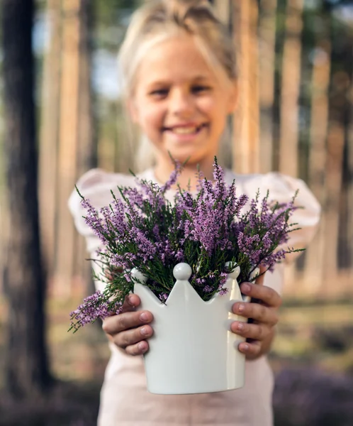 Hermosa chica en el bosque sosteniendo en un jarrón con brezo . — Foto de Stock